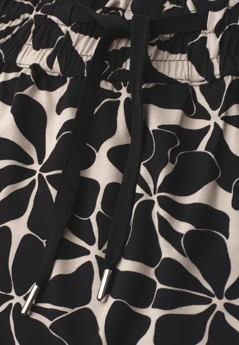 Schwarz-beige Stoff mit abstraktem, großblättrigem Blumendruck und elastischem Bund mit Kordelzug.