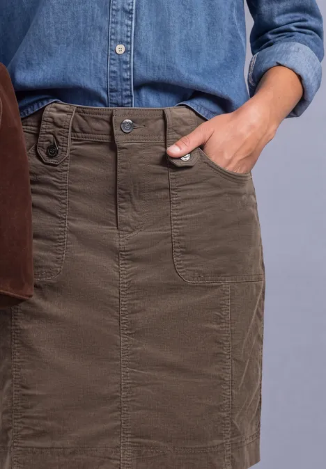 Close-up van een kaki rok met zakken, gedragen met een jeansbloes.