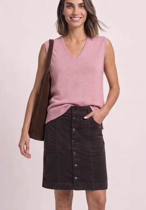Vrouw draagt roze mouwloos V-hals top, donker knielang knooprokje en een bruine tas.