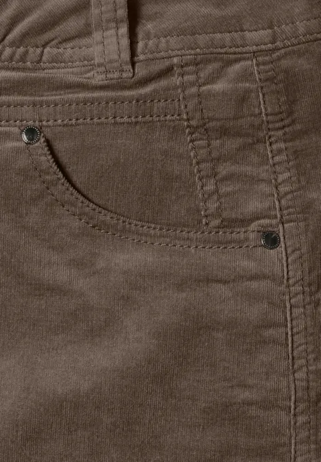 Nahaufnahme einer braunen Cordhose mit Tasche, sichtbaren Nähten, Gürtelschlaufen und Metallnieten.