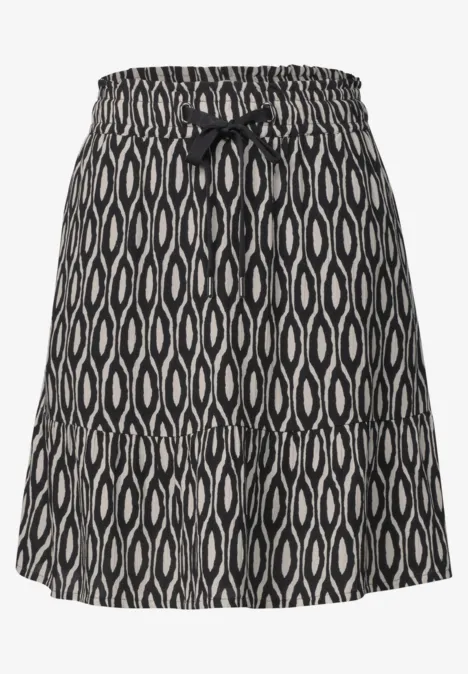 Korte zwarte rok met wit organisch patroon, elastische tailleband en sierstrik aan de voorkant.