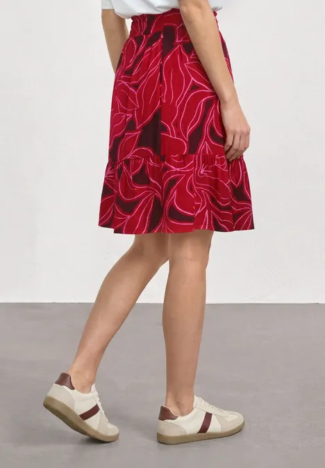 Knielanger Rock mit Print und Volant salsa red Person trägt roten, floralen Rock und weiße Sneaker, blickt seitlich.