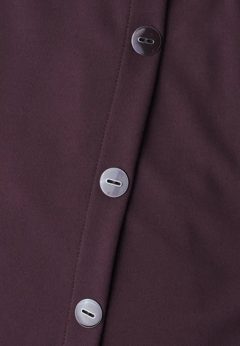 Nahaufnahme eines dunkelvioletten Kleidungsstücks mit drei silbernen Knöpfen.