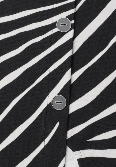 Gros plan d'un tissu à rayures noir et blanc avec une patte de boutonnage et des boutons gris.