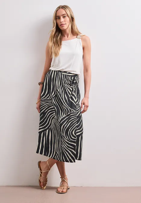 Midirok in wikkel-look met print Black Vrouw met wit topje en zwart-witte midirok voor een witte muur