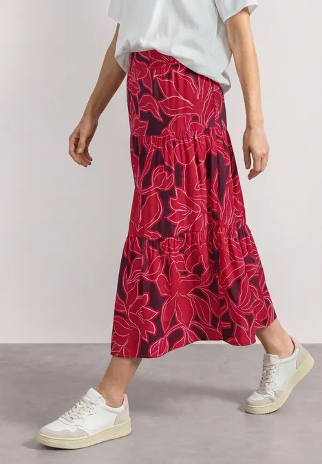 Maxi-Rock mit Volants und Print salsa red Eine Person trägt weißen T-Shirt, roten Midirock mit Blumenmuster und weiße Sneaker.