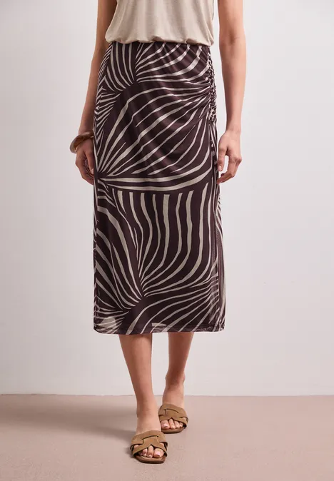 Midirok van mesh met print rustic rouge Vrouw in beige top en midi-rok met bruin-beige zebraprint, gecombineerd met platte sandalen.