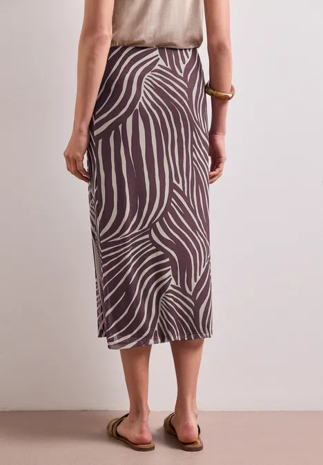 Midirok van mesh met print rustic rouge Vrouw van achteren in een midi-rok met bruin-beige zebraprint en platte sandalen.