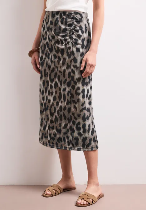 Midirok van mesh met print timeless beige Vrouw draagt een midirok in luipaardprint en gouden sandalen.