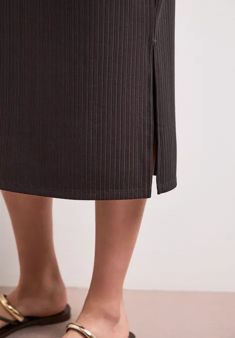 Geribde midirok met elastische tailleband espresso brown Iemand draagt een zwarte geribbelde midirok met een split en gouden sandalen.
