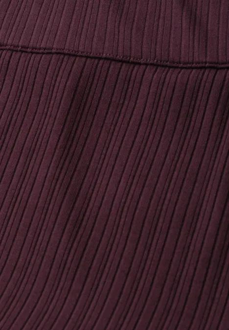 Geribde midirok met elastische tailleband rustic rouge Close-up van een donker bordeauxrode, geribbelde stof met naad.