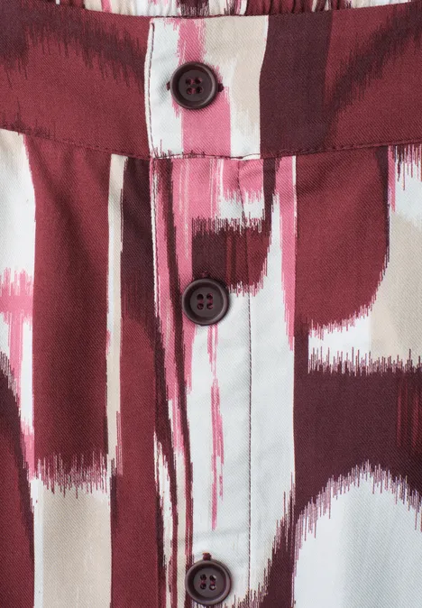 Midi-Rock mit Knopfleiste und Print rustic rouge Detail eines Hemds mit rot-weißem Pinselstrichmuster und drei dunklen Knöpfen.