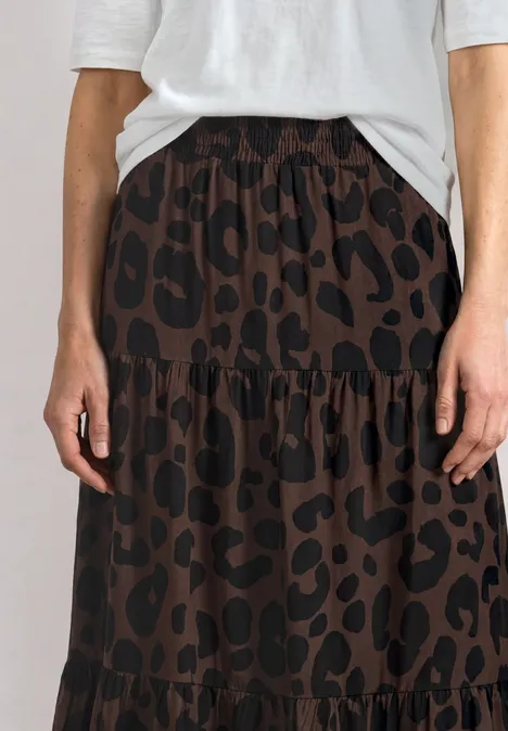 Maxi-Rock mit Volants und Print molten earth Weiblicher Körper mit weißem Oberteil und braunem Rock mit schwarzem Leopardenmuster.