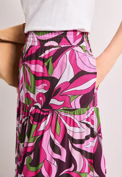 Maxi-Rock mit Volants und Print magenta dream Lang geschnittener Rock mit elastischem Bund und auffälligem psychedelischem Muster in Pink, Lila und Grün.