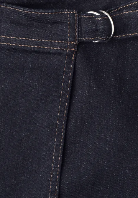 Kniefreier Denim Rock in Wickeloptik Rinse Blue washed Dunkle Jeans mit Gürtel und silbernem D-Ring an der Taille.
