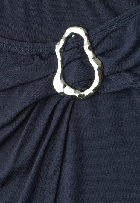 Donkerblauwe stof met een zilverkleurige, decoratieve ring die plooien vormt.