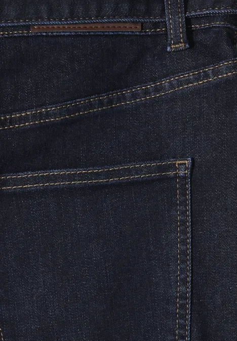 Nahaufnahme einer dunkelblauen Jeanshose, Detail der Gesäßtasche mit gelben Ziernähten.
