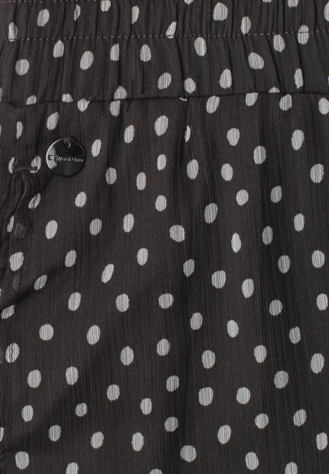 Zwarte stof met witte polkadots, voorzien van een zijzak met metalen knoop.