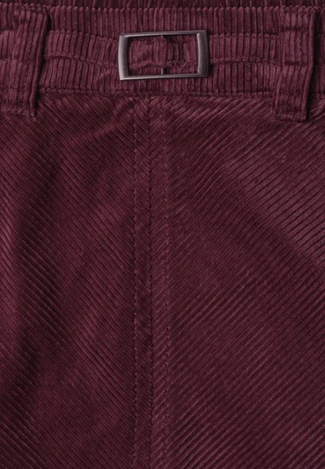 Nahaufnahme einer weinroten Cordhose mit Gürtel und feinem Rippenmuster