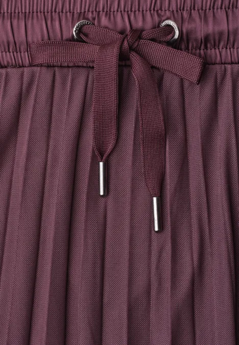 Midirock aus Mesh in Plisséestruktur rustic rouge Nahaufnahme eines bordeauxfarbenen, plissierten Rocks mit elastischem Bund und Schleife.