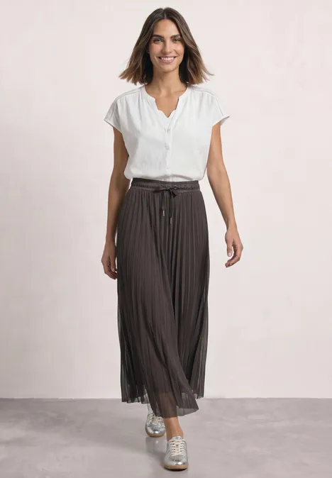 Midirock aus Mesh in Plisséestruktur black coffee Frau in weißer Bluse mit kurzen Ärmeln und braunem, plissiertem Midirock mit Gürtel.