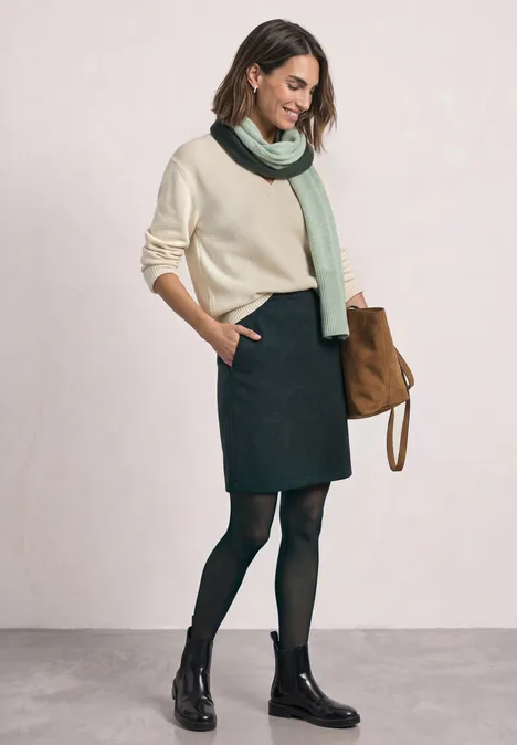 Knielanger Rock in Wolloptik stormy green Frau in beigem Pullover, grünem Schal, dunklem Rock, schwarzen Strumpfhosen und Boots mit brauner Tasche.