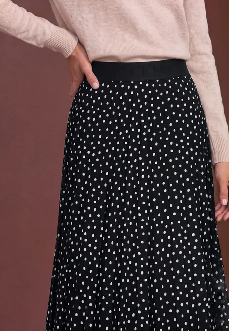 Schwarzer, weit schwingender Rock mit weißen Polka Dots, kombiniert mit leicht rosafarbenem Oberteil