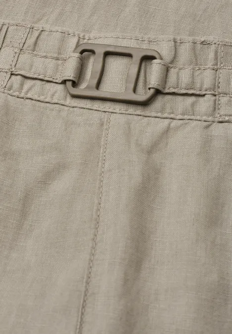 Close-up van een kaki kledingstuk met elastische tailleband en gesp.