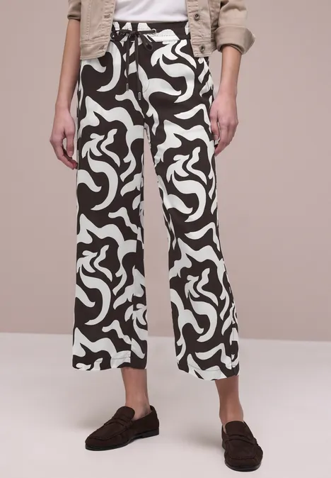 Schwarz-weiße Culotte mit abstraktem Muster, hohem Bund und weitem Schnitt, getragen mit dunklen Loafers.