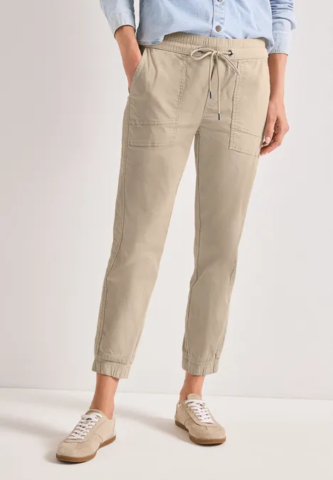 Lichtbeige linnenbroek met trekkoord, opgestikte zakken en opgerolde pijpen voor een nonchalante look.
