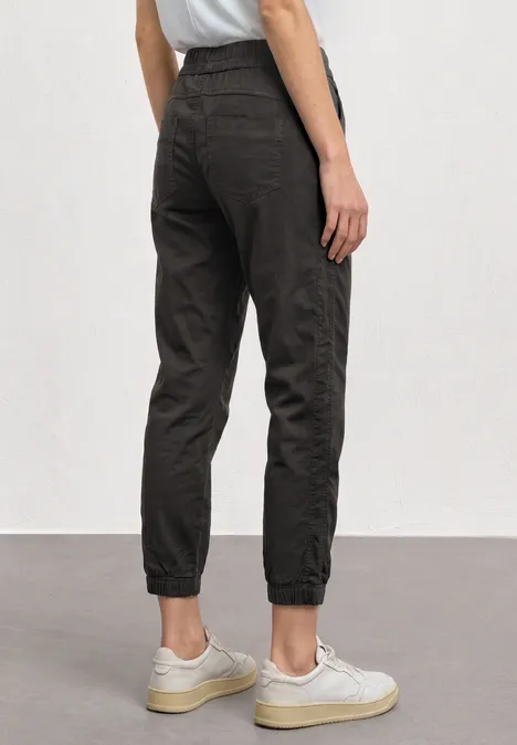 Donkere joggerbroek met hoge, elastische pijpzomen, losse pasvorm, rugaanzicht, gecombineerd met witte sneakers.