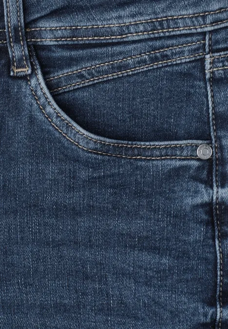 Mid Waist Slim Leg Jeans im Slim Fit brilliant indigo random wash Jeanshose in dunklem Blau mit sichtbarer Tasche und Nahtdetails.