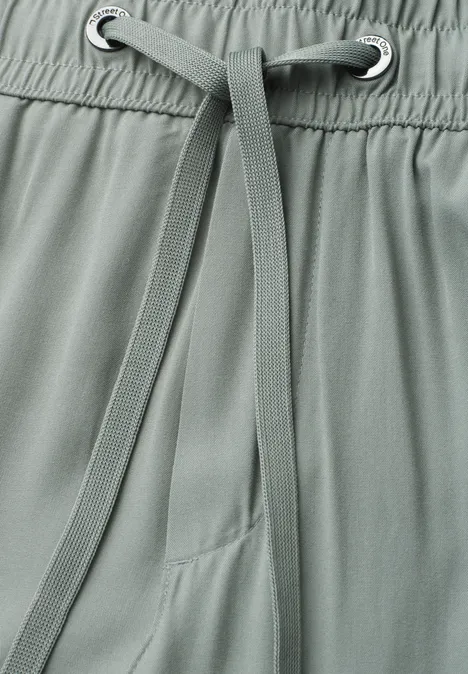 Detailaufnahme einer graugrünen Hose mit Kordelzug und Gummibund
