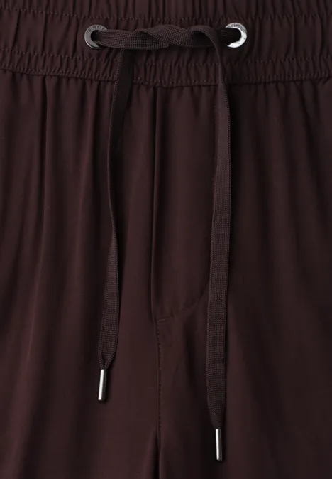 Bruine broek met elastische taille en trekkoorden, close-up van het taillegebied.