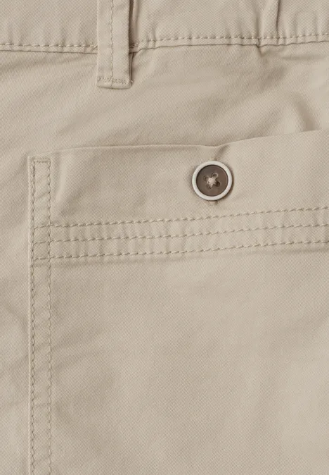 Close-up van een beige katoenen broek met een knoopsluiting op de achterzak en zichtbare stiksels.
