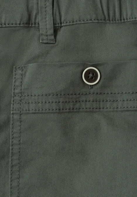 Close-up van een groene broek met zijzak en knoop.