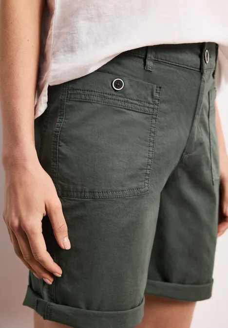Donkergroene chino-short met opgerolde zoom en zakken, zicht vanaf heup tot bovenbeen.