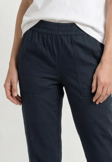 Slim Leg Chino mit Elastikbund shadowed navy Frau trägt navyblaue, lässige Hose mit Gummizugbund und Seitentaschen vor weißem Hintergrund.
