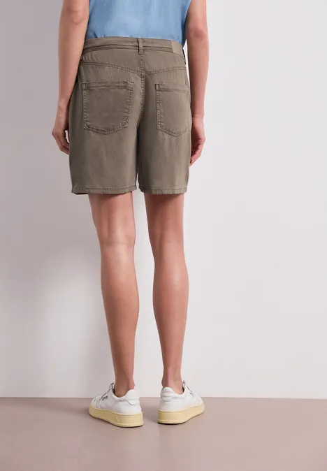 Straight Leg Shorts im Casual Fit brown wash Person von hinten in khakifarbenen Shorts und weißen Turnschuhen, stehend vor neutralem Hintergrund.