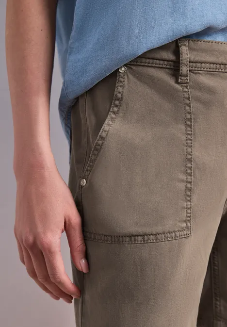 Straight Leg Shorts im Casual Fit brown wash Nahaufnahme einer Hand an der Tasche khakifarbener Hose und einem hellblauen Oberteil