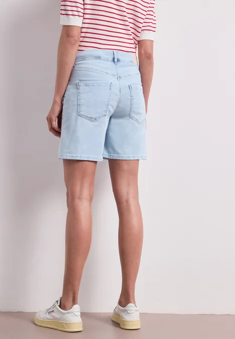 Straight Leg Shorts im Casual Fit bleached light blue wash Eine Person steht mit hellblauen Jeansshorts, rotem gestreiften Oberteil und weißen Sneakern vor einer Wand.