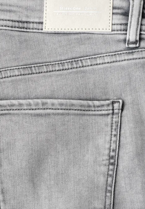 Detailfoto van een lichtgekleurde spijkerbroek van achteren, met achterzak, riemlussen en een onbedrukt leren label.