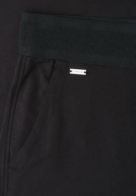 Schwarze Hose mit elastischem Bund, seitlicher Tasche und kleinem Metalllogo.