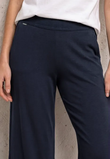 Person trägt weite dunkelblaue Hose mit seitlicher Reißverschlusstasche, lässiger Schnitt.