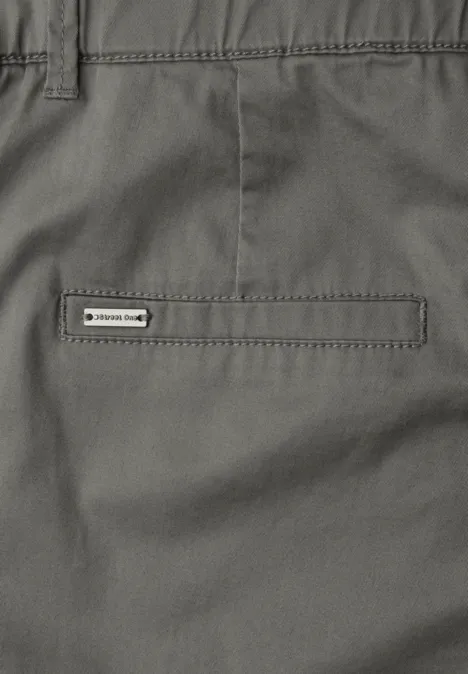 Close-up van een grijze broek met een simpele achterzak en een klein merkje.