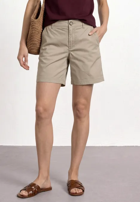 Mid Waist chino shorts in een casual pasvorm buff grey Vrouw met kaki short, bruine sandalen en een rieten tas over de schouder.
