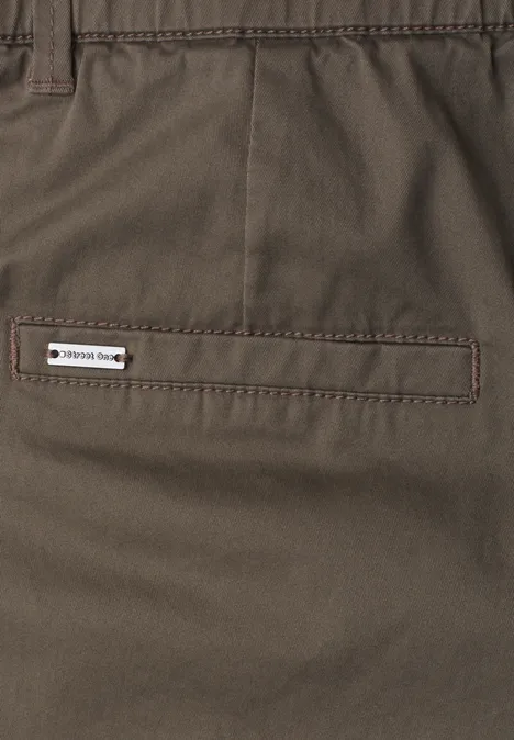 Mid Waist Chino Shorts im Casual Fit cold brew brown Braune Hose mit gestepptem Gesäßtascheneingriff und kleinem weißen Label 'TREKKING SHOP'.