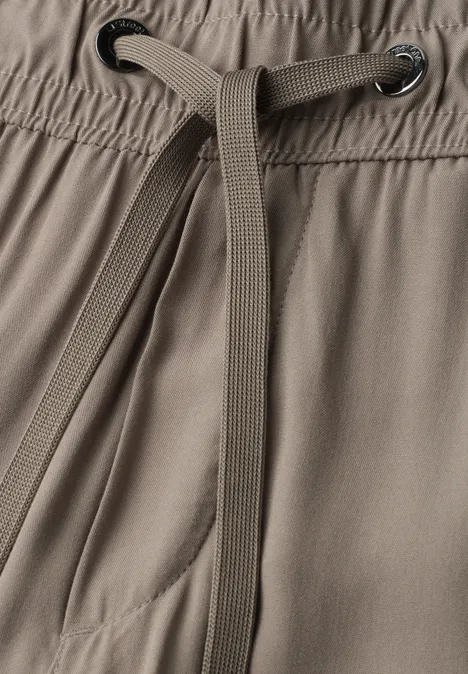 Nahaufnahme eines Tunnelzugs und Bunds einer graubraunen Hose mit Tasche