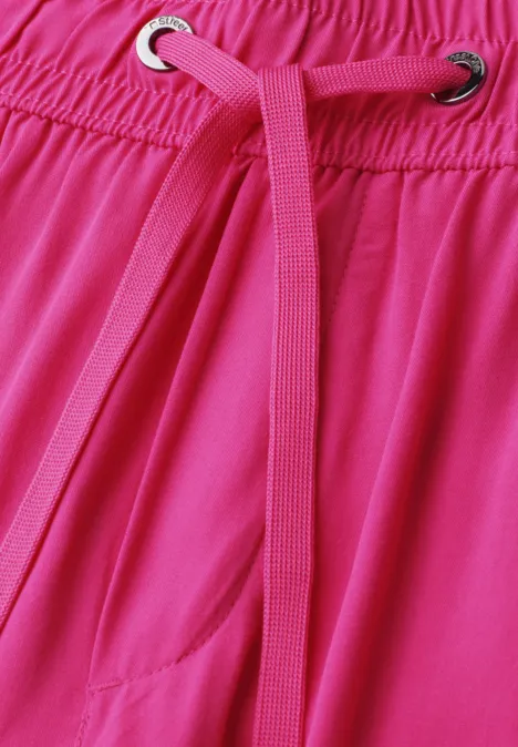 Nahaufnahme eines pinken Kleidungsstücks mit elastischem Bund und pinker Kordel durch Metallösen.