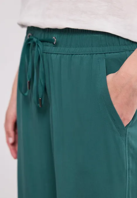 Grüne, locker sitzende Hose mit elastischem Bund, Kordelzug und seitlicher Tasche.